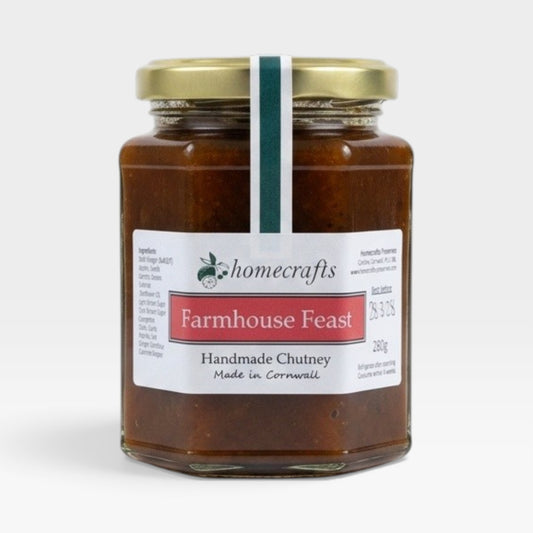A glass jar of Homecrafts Farmhouse Feast Handmade Chutney with a gold lid and white label, set against a plain light gray background.