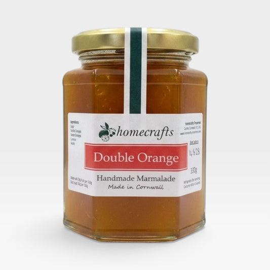 A glass jar of Homecrafts Double Orange Handmade Marmalade with a gold lid and white label, set against a plain light gray background.